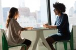 Two women sitting at table speaking