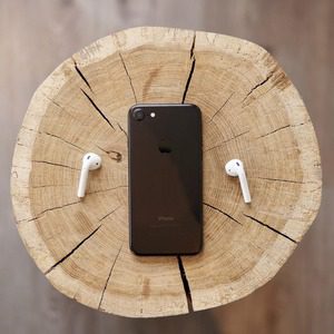 iPhone and airpods on wooden stump